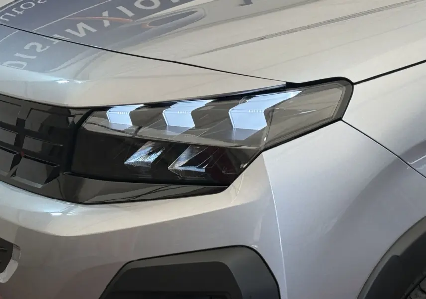 Gros plan sur le phare avant droit du Peugeot Rifter gris clair 2024 avec calandre noire et détails LED distinctifs.