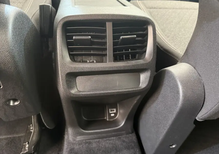 Détail de la console arrière noire avec bouches d’aération et prise USB du Peugeot Rifter gris clair 2024.