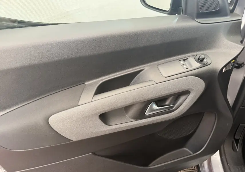 Gros plan sur la porte avant gauche du Peugeot Rifter gris clair 2024, avec commandes électriques et poignée intégrée.