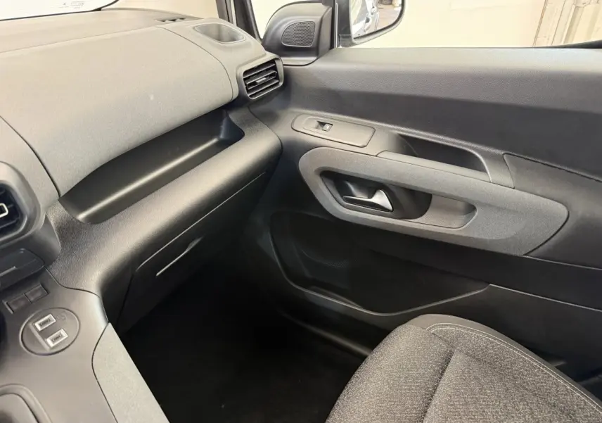 Vue intérieure côté passager du Peugeot Rifter 2024 gris clair, montrant la portière et le tableau de bord minimaliste.
