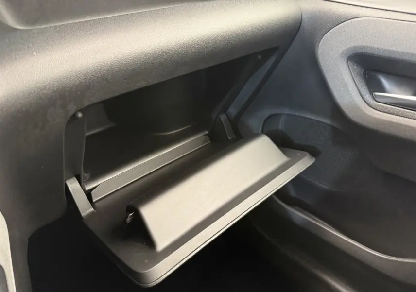 Vue rapprochée de la boîte à gants ouverte côté passager du Peugeot Rifter 2024, intérieur noir.