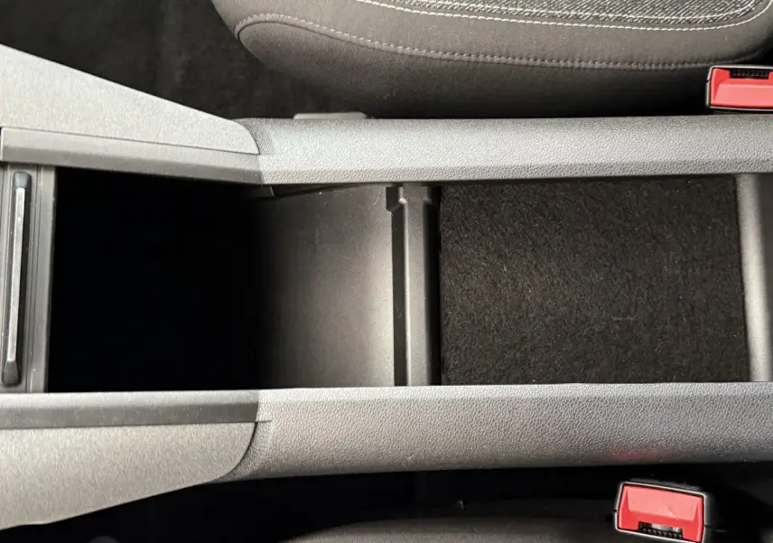 Vue rapprochée de la console centrale grise du Peugeot Rifter 2024 avec ouverture de rangement entre les sièges avant.