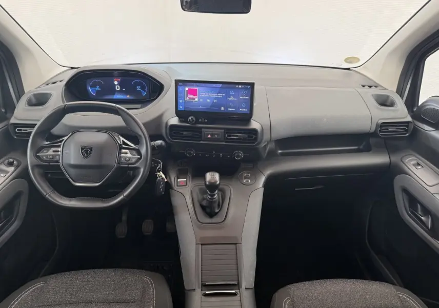 Vue intérieure avant du Peugeot Rifter 2024, tableau de bord moderne avec écran tactile central et volant cuir multifonctions.