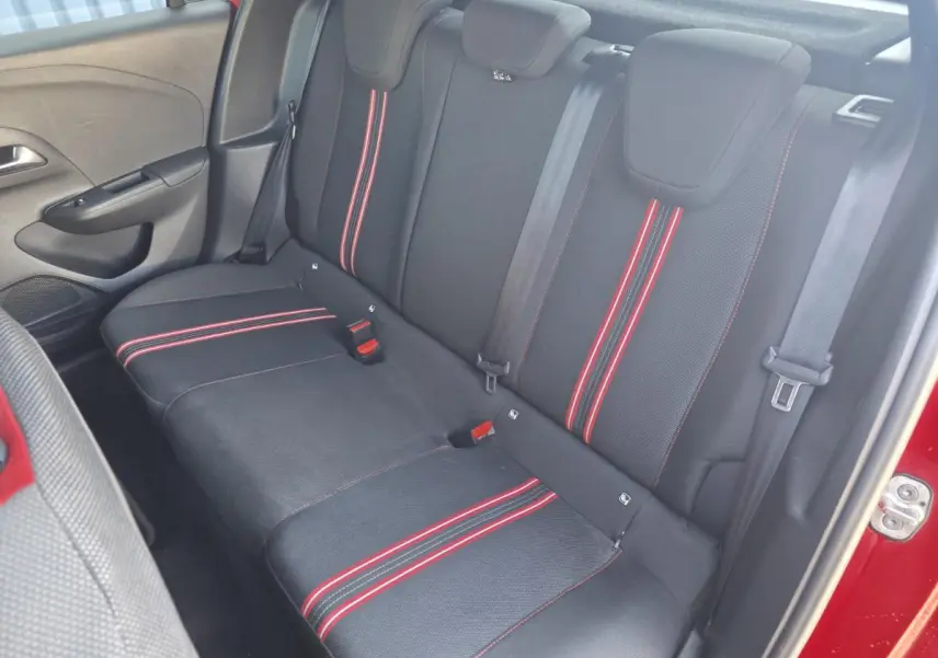 Vue intérieure côté droit de la banquette arrière noire avec bandes rouges sur une Opel Corsa rouge.