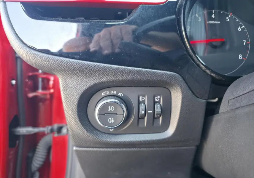 Détail des commandes d’éclairage côté gauche sur tableau de bord d’une Opel Corsa rouge 2020.