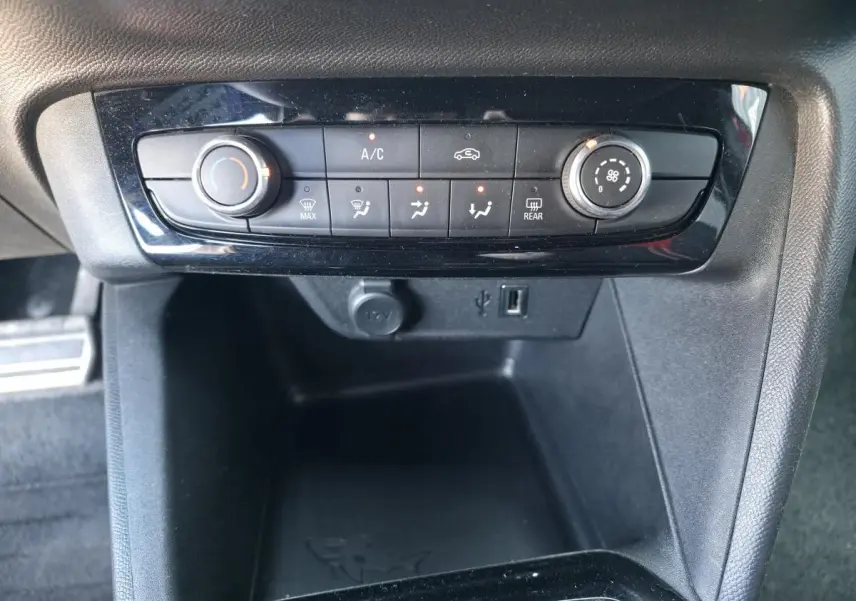 Vue rapprochée de la console centrale noire de l’Opel Corsa 1.2i Turbo avec commandes de climatisation et prise USB.