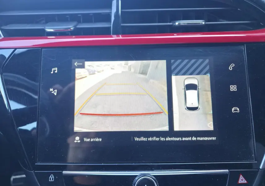 Écran tactile intérieur montrant la caméra de recul et la vue à 180° de l’Opel Corsa rouge en stationnement.