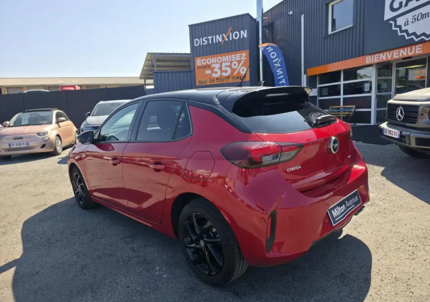 Opel Corsa rouge 3/4 arrière droit avec toit noir brillant et jantes alliage noires visibles.
