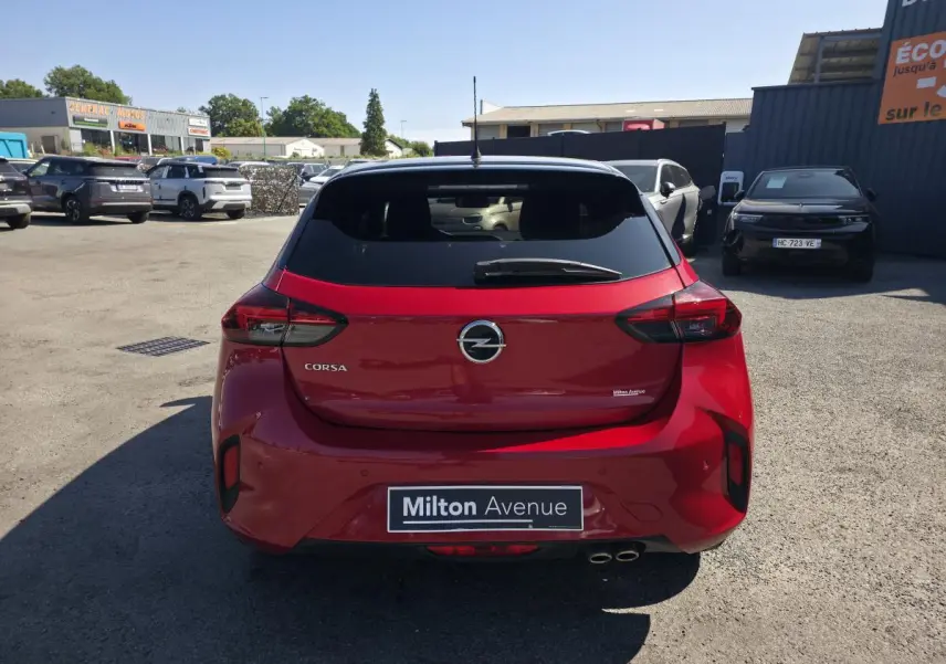 Vue arrière d'une Opel Corsa rouge 2020 avec toit noir et double sortie d'échappement chromée, stationnée en extérieur.