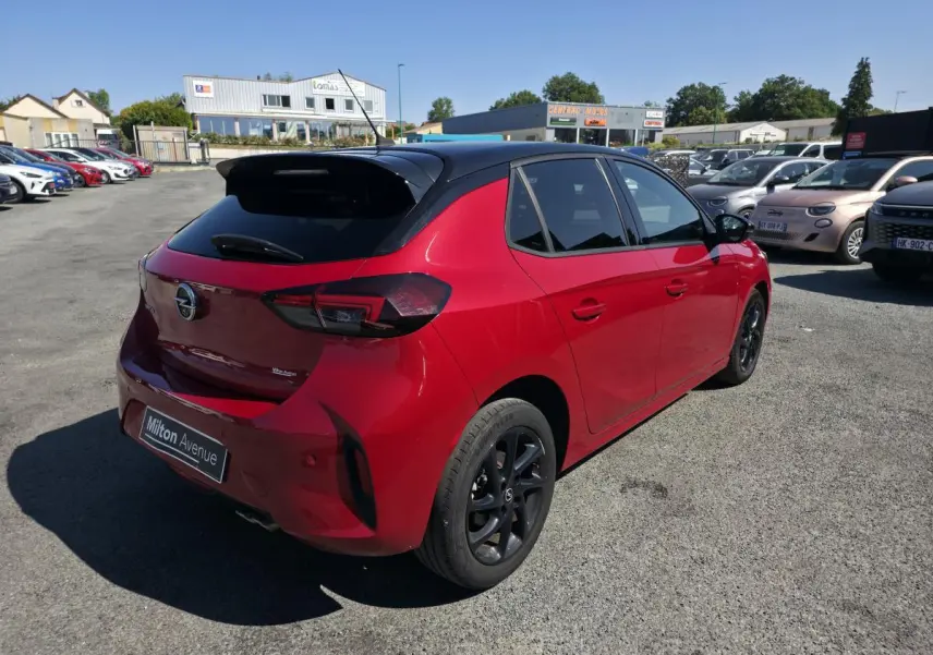 Opel Corsa rouge 3/4 arrière droit avec toit noir, jantes noires et vitres arrière surteintées.