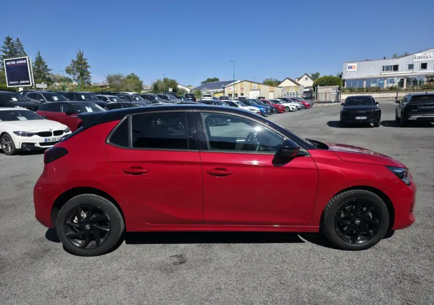 Opel Corsa rouge vue de profil côté gauche avec jantes noires et vitres arrière surteintées.