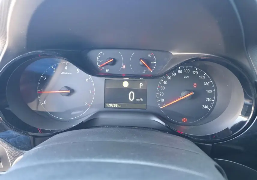 Vue rapprochée du tableau de bord de l'Opel Corsa rouge, affichant la vitesse à 0 km/h et le compteur moteur.