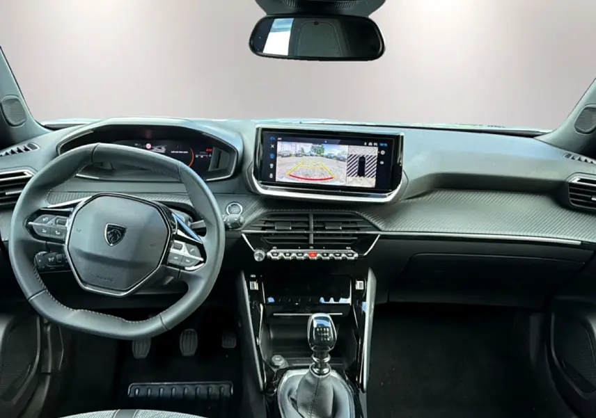 Vue intérieure avant du Peugeot 2008 1.2 100 allure avec volant multifonction, écran tactile et levier de boîte manuelle.