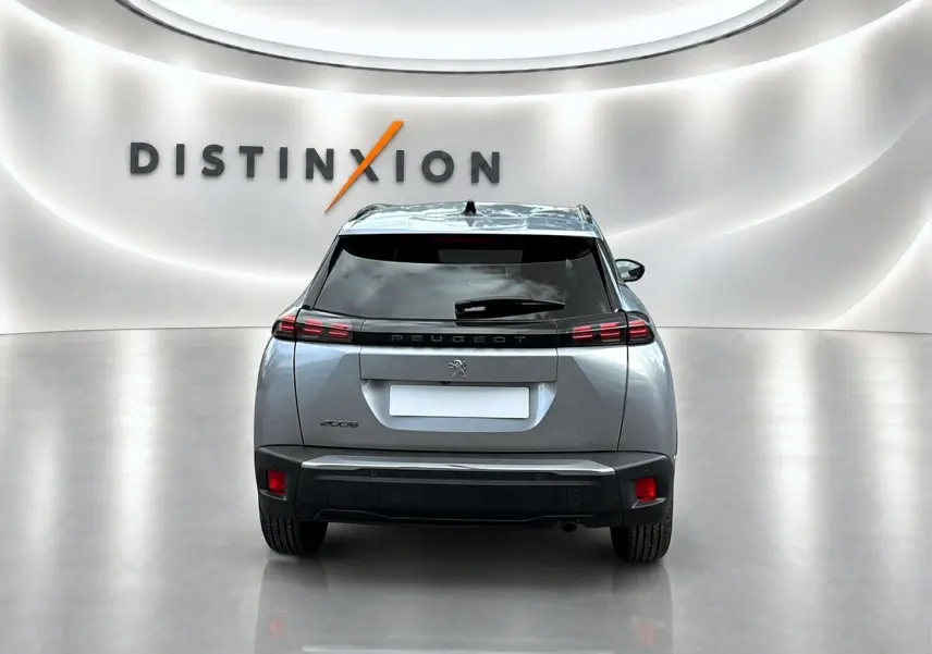 Vue arrière centrée du Peugeot 2008 gris Artense 2025 avec feux LED et lunette arrière teintée dans un showroom lumineux.
