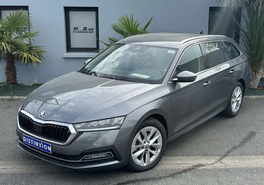 Vue 3/4 avant droite d'une Skoda Octavia Combi gris graphite avec calandre chromée et barres de toit argentées.