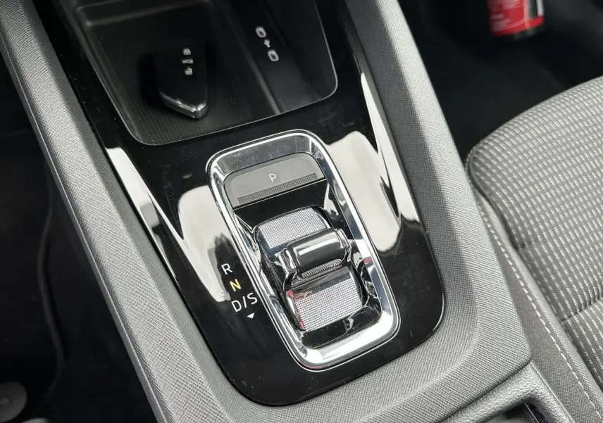 Gros plan sur la console centrale noire brillante de la Skoda Octavia Combi 2024 avec levier de boîte automatique et siège tissu gris.