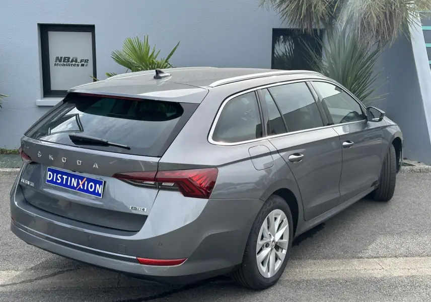 Vue 3/4 arrière droite d'une Skoda Octavia Combi gris graphite avec feux arrière LED et attelage amovible.
