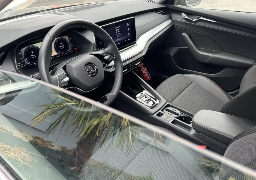 Intérieur côté conducteur de la Skoda Octavia Combi 2024, volant cuir multifonctions et écran tactile central visible.