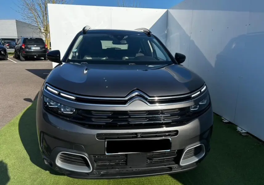 Vue frontale d'un Citroën C5 Aircross gris platinium métallisé avec calandre noire brillante et projecteurs LED.