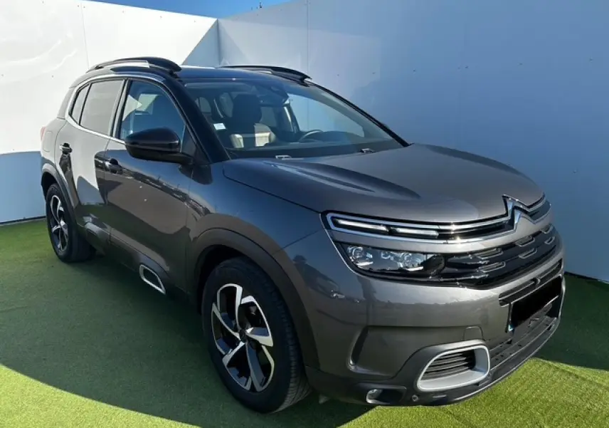 Citroën C5 Aircross gris platinium métal en 3/4 avant droit avec jantes alliage et barres de toit noires.