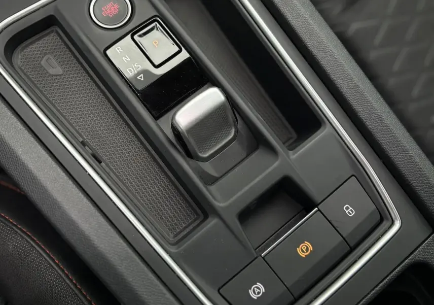 Vue rapprochée de la console centrale noire avec levier de boîte auto et bouton Start du SEAT LEON 1.5 e-TSI 2024.