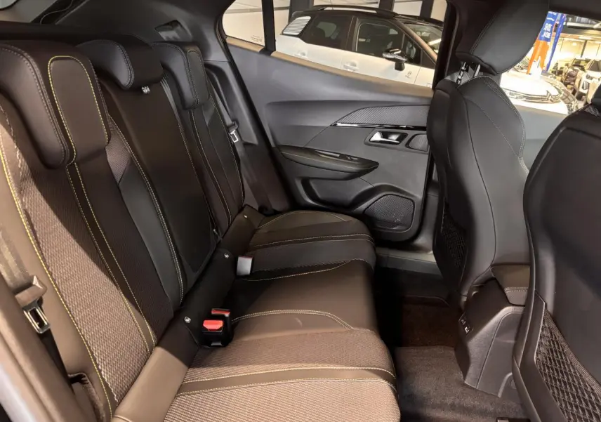Vue intérieure arrière droite du Peugeot 2008 noir, montrant la banquette avec surpiqûres vertes et les panneaux de porte.