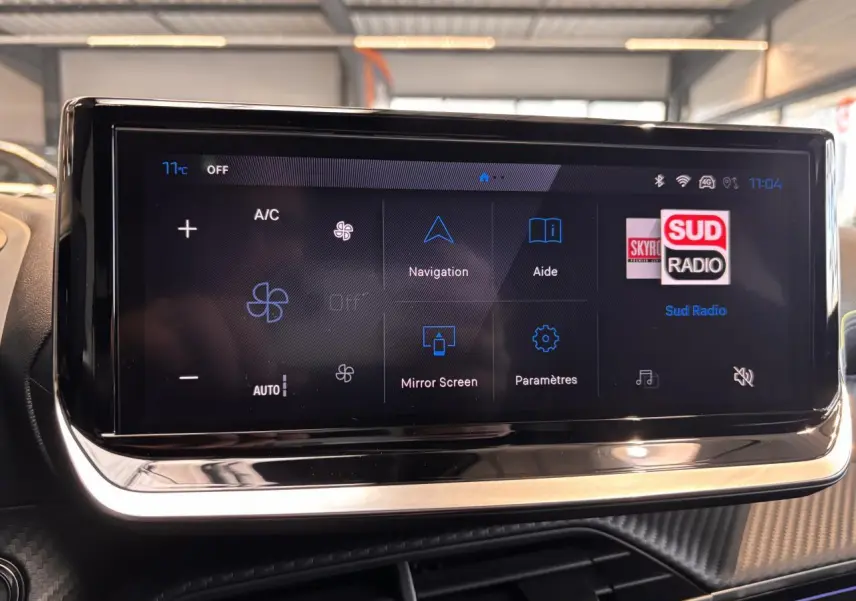 Écran tactile central du Peugeot 2008 noir, affichant les commandes de climatisation et navigation en intérieur lumineux.