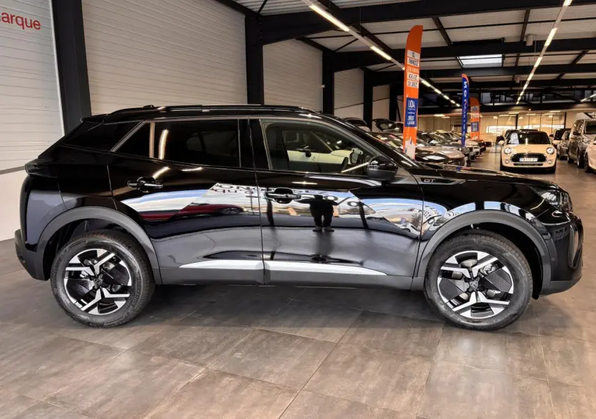 Profil côté gauche du Peugeot 2008 noir brillant avec jantes alliage bi-ton et toit Black Diamond en showroom.