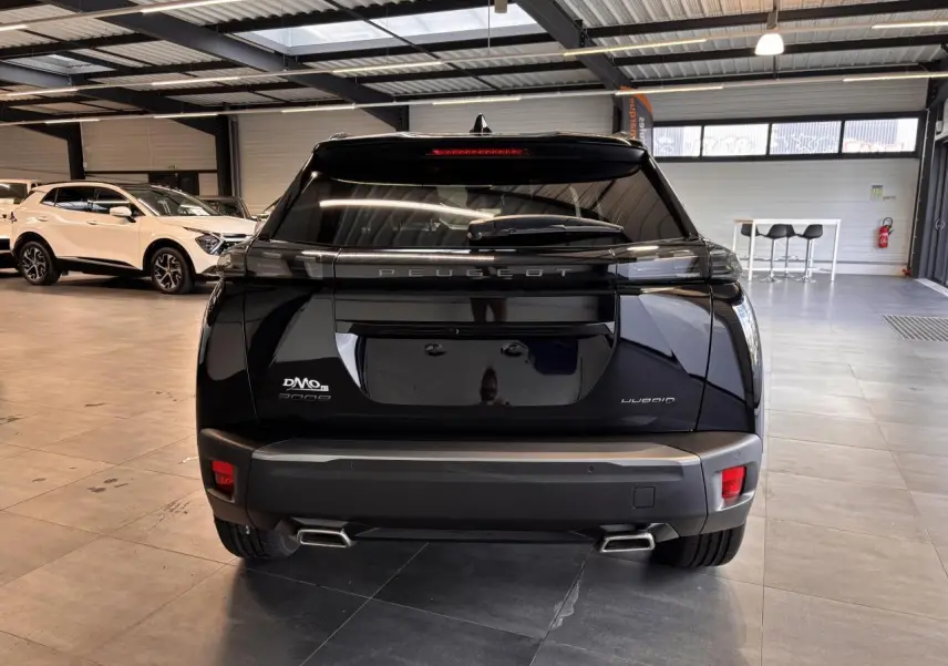 Vue arrière d'un Peugeot 2008 noir hybride exposé en showroom, avec double sortie d'échappement chromée et feux LED.