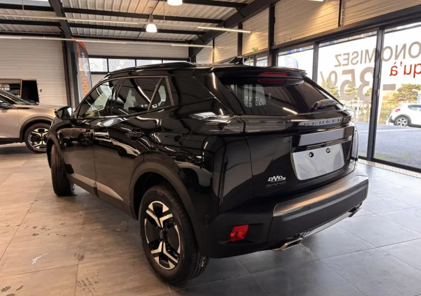 Vue 3/4 arrière droite d'un Peugeot 2008 noir brillant en showroom avec feux arrière LED et jantes bi-ton.