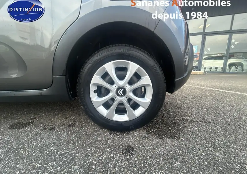 Gros plan sur la roue avant droite d'une Citroën C3 gris foncé avec jante alliage et logo Citroën visible.