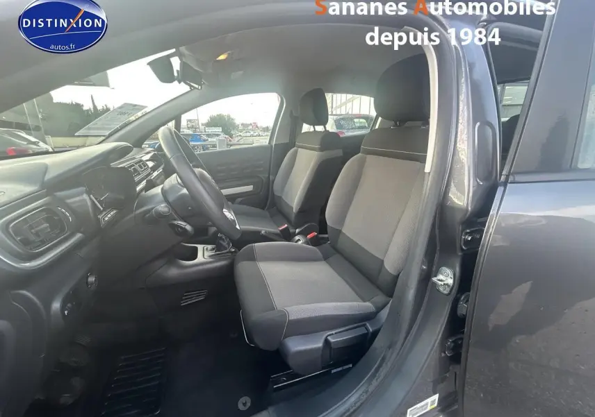 Vue intérieure côté conducteur d'une Citroën C3 gris foncé 2023 avec sièges tissu Mica Grey et boîte manuelle.