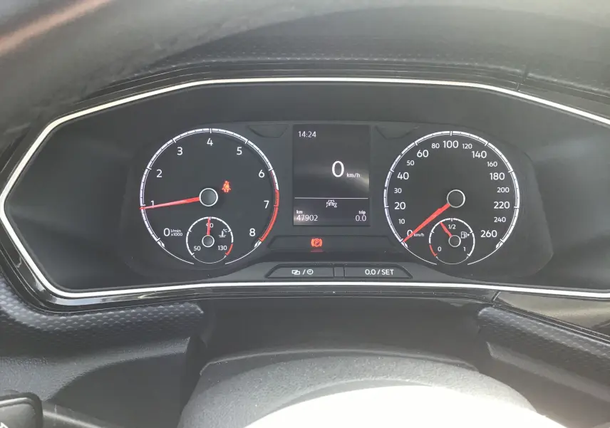 Vue rapprochée du tableau de bord numérique du Volkswagen T-Cross blanc, affichant vitesse et compte-tours.