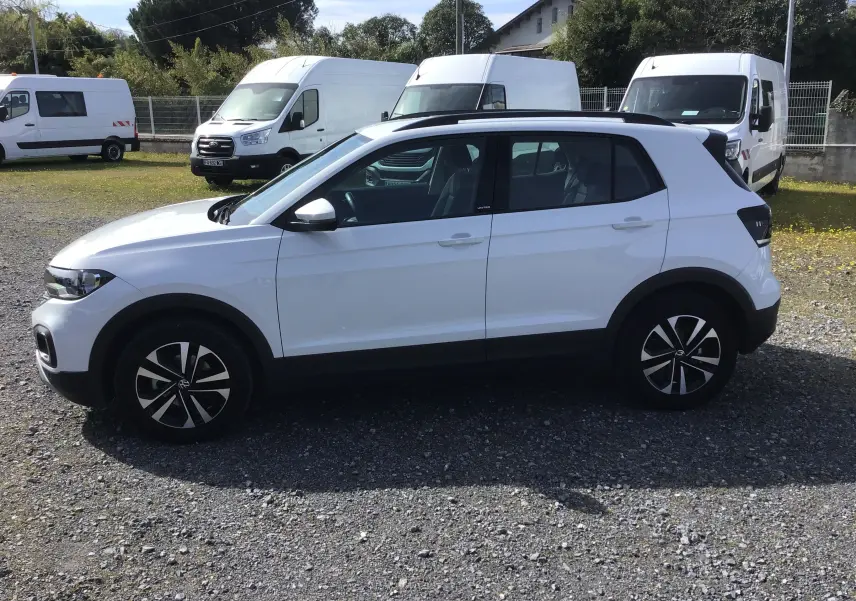 Vue de profil côté gauche d’un Volkswagen T-Cross blanc 2021 avec jantes alliage noires et toit noir contrasté.