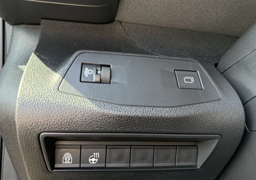 Gros plan sur le volant cuir gris clair du Peugeot Rifter 2026 avec commandes multifonctions et logo Peugeot noir brillant.