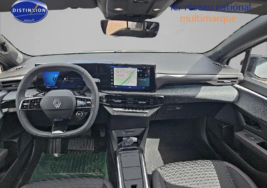 Vue intérieure avant de la Renault Clio VI gris rafale, tableau de bord moderne avec écran tactile et volant multifonctions.