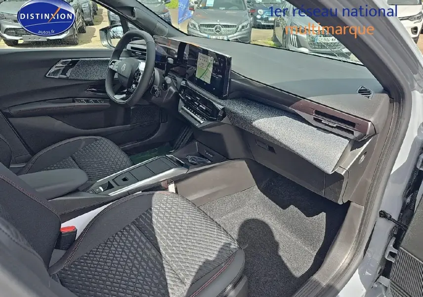 Vue intérieure côté passager avant de la Renault Clio VI gris rafale, avec tableau de bord moderne et écran tactile central.