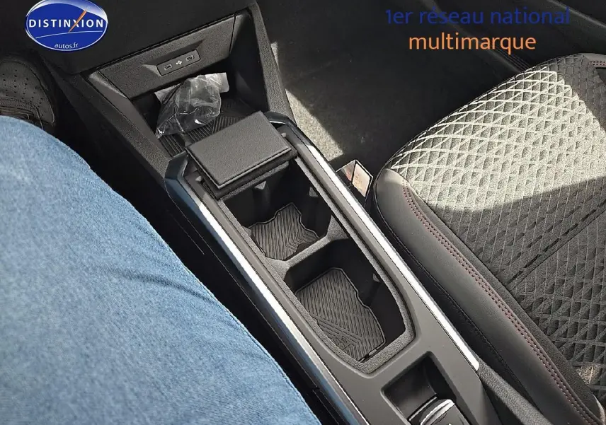 Vue rapprochée de l'accoudoir central avec rangement et console de la Renault Clio VI gris rafale, sièges tissu noir.