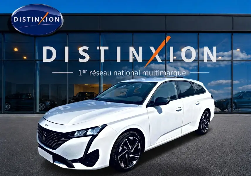 Peugeot 308 SW blanche vue en 3/4 avant droit, avec jantes alliage noires et toit vitré, devant une vitrine Distinxion.