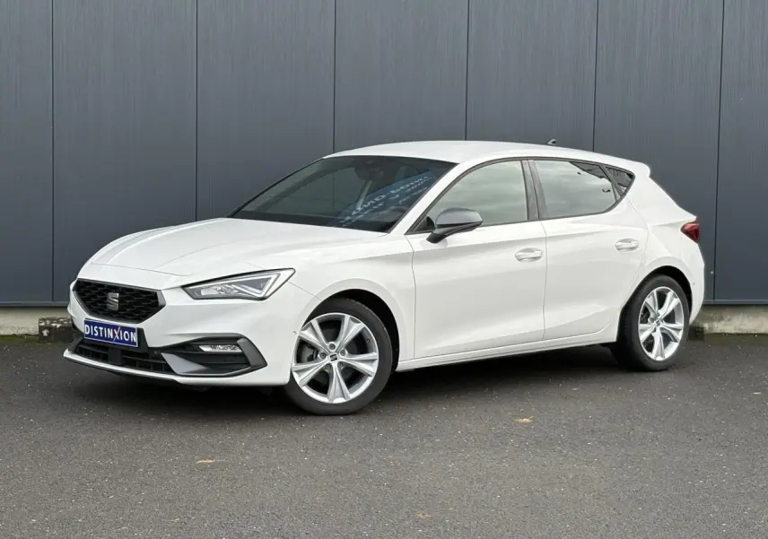 Vue 3/4 avant droite d'une SEAT Leon 1.5 e-TSI 150 DSG7 FR blanche avec jantes alliage 17 pouces et vitres surteintées.