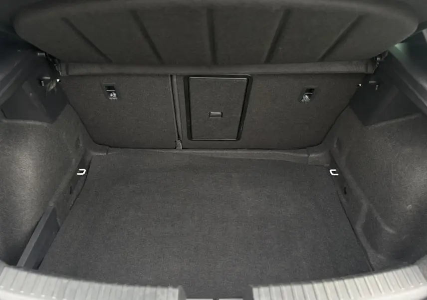 Coffre spacieux et vide de la SEAT LEON 1.5 e-TSI 150 DSG7 FR, vue intérieure arrière avec revêtement gris foncé.