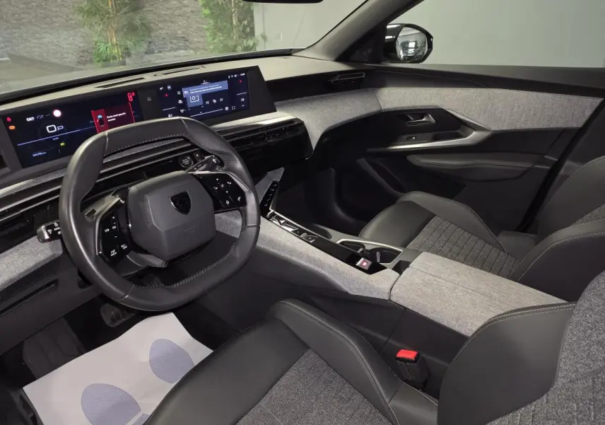 Intérieur avant droit du Peugeot 3008 gris 2025, avec tableau de bord numérique et sellerie tissu gris et cuir noir.