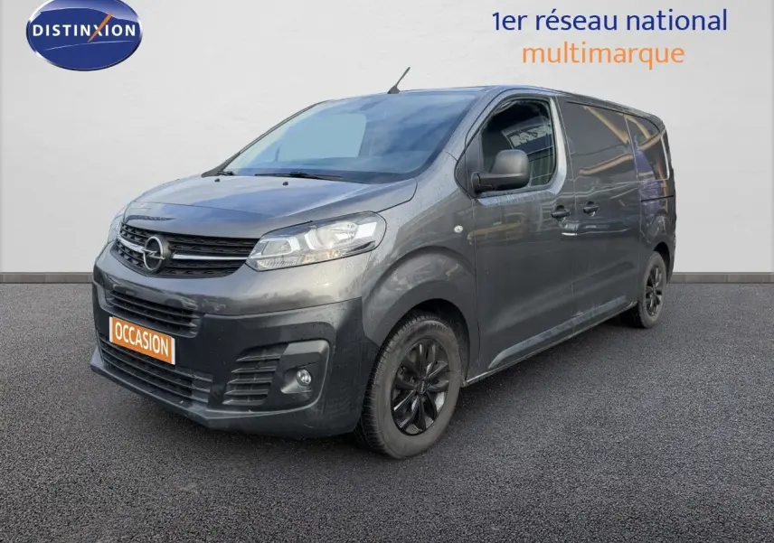 Opel Vivaro gris titane métal en 3/4 avant droit, avec jantes noires et calandre noire distinctive.