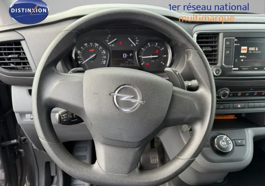 Vue intérieure centrée sur le volant Opel Vivaro 2.0 180CH gris titane, avec tableau de bord et écran multimédia visibles.