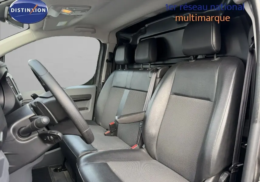 Vue intérieure côté conducteur de l’Opel Vivaro 2.0 gris titane, montrant les sièges avant en tissu et cuir noir.