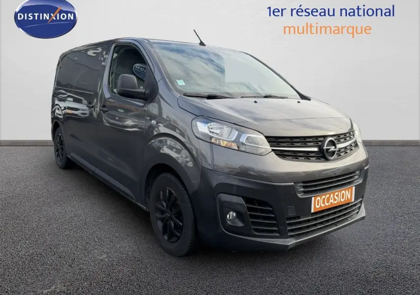Opel Vivaro gris titane métal vu en 3/4 avant droit, fourgon utilitaire avec jantes noires et calandre distinctive.