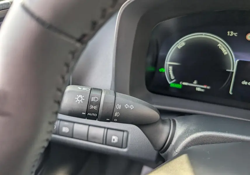 Gros plan sur le commodo d’éclairage à gauche du volant dans l’habitacle du Toyota C-HR blanc 2024.