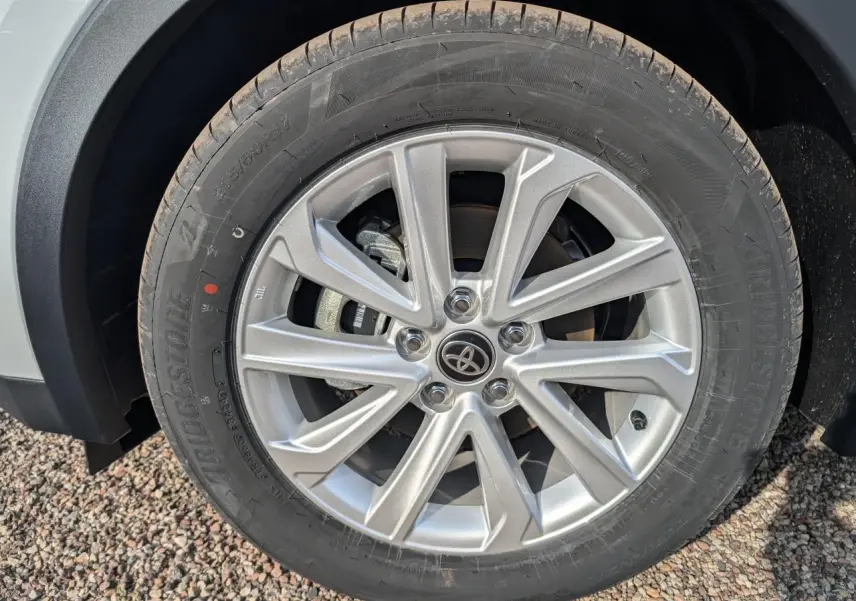 Gros plan sur la jante alliage 17 pouces argentée du Toyota C-HR blanc, avec logo Toyota au centre.