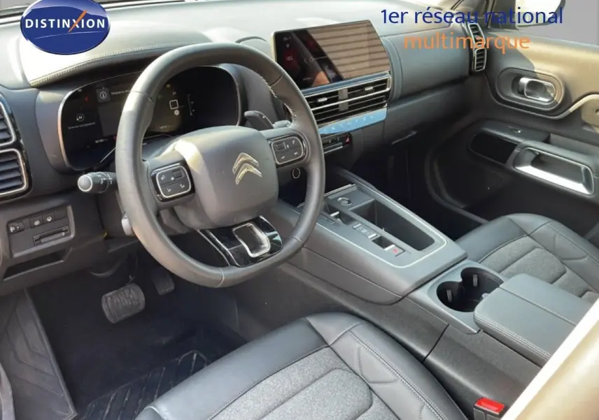 Intérieur de Citroën C5 Aircross 2025 vu côté conducteur, avec tableau de bord numérique et sellerie tissu cuir gris noir.