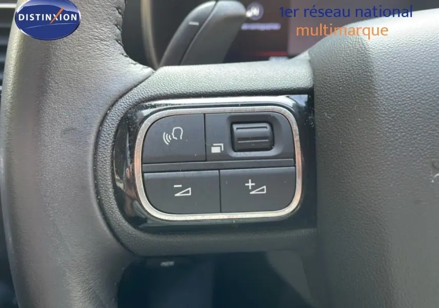 Gros plan sur les commandes vocales et volume au volant cuir noir du Citroën C5 Aircross 2025 bleu Eclipse Metal.